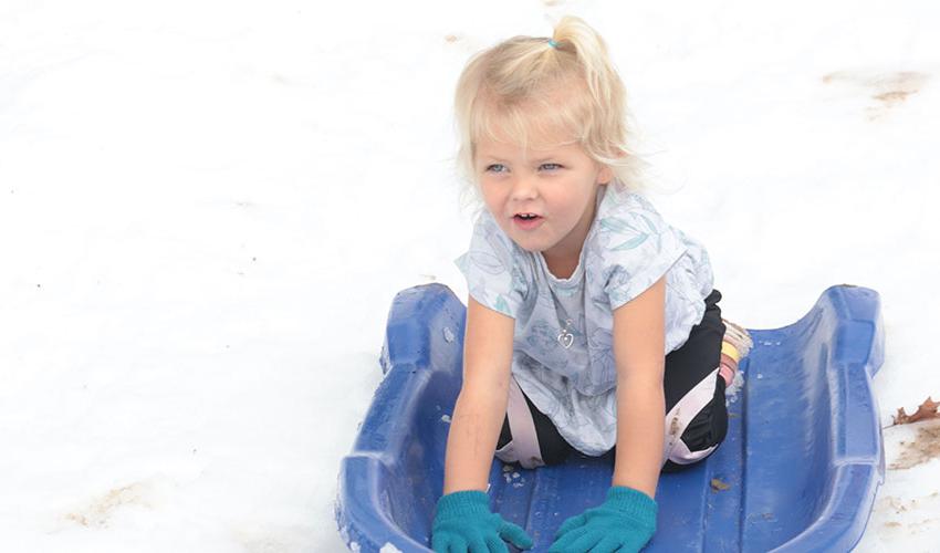 Little girl sliding down the snow hill