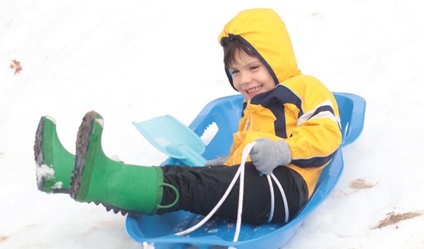 Little boy sliding down the snow hill