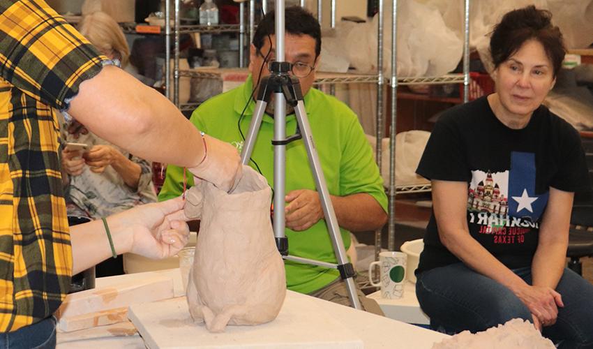 Students observing Mrs. Jeanne making a sculpture.